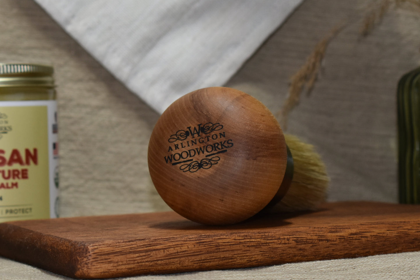 Artisan Furniture Wood Balm jar with a brush and towel on a wooden surface